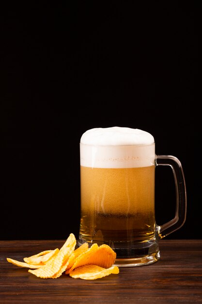 Jarra de cerveza con patatas fritas en el tablero de madera