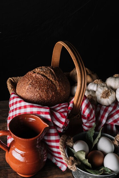 Jarra y huevos cerca de la canasta con comida