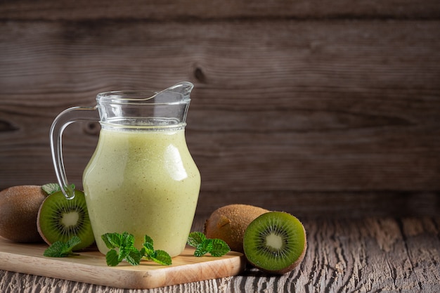 Jarra de jugo de kiwi en tabla para cortar madera