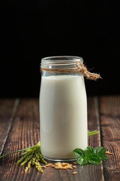 Jarra de leche de arroz con planta de arroz y semilla de arroz puesta sobre un piso de madera