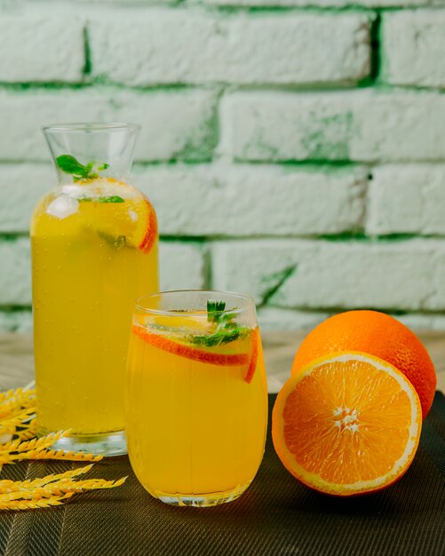 Jarra de limonada cítrica vidrio menta naranja agua con gas vista lateral