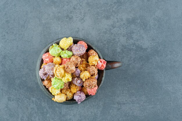 Jarra de metal llena de dulces de palomitas de maíz sobre fondo de mármol. Foto de alta calidad