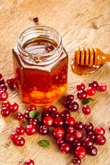 Jarra de miel de alto ángulo y frutas rojas