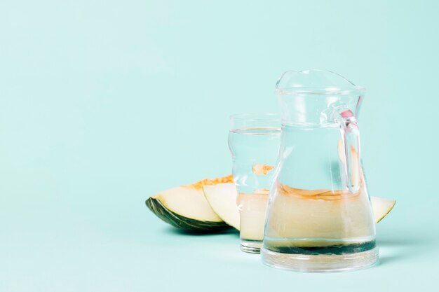 Jarra y vaso de agua con rodajas de melón