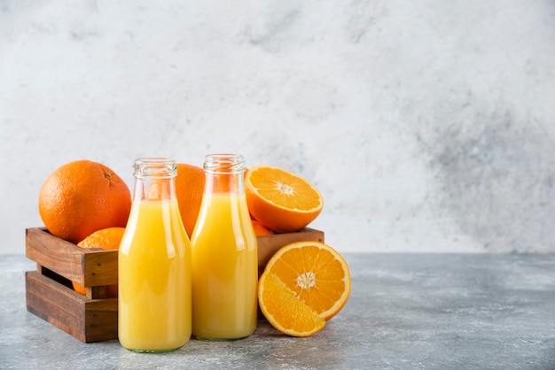 Una jarra de vidrio de jugo con frutas frescas de naranja en la mesa de piedra.