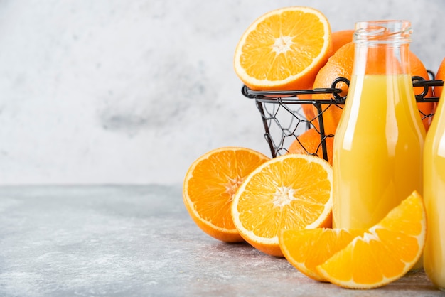 Foto gratuita una jarra de vidrio de jugo con frutas frescas de naranja en la mesa de piedra.