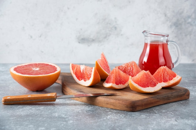 Jarra de vidrio de jugo de pomelo fresco con rodajas de frutas.