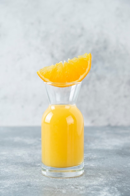 Jarra de vidrio de jugo con rodaja de naranja.