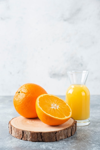 Jarra de vidrio de jugo con rodajas de naranja sobre una tabla de madera.