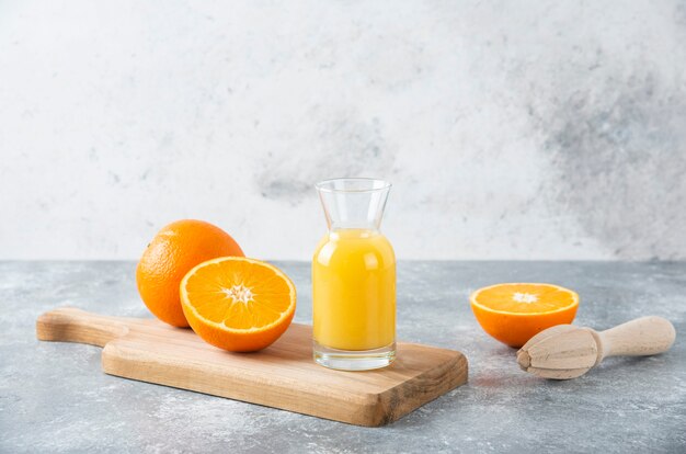 Jarra de vidrio de jugo con rodajas de naranja sobre una tabla de madera.