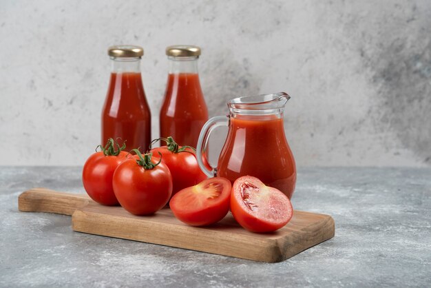 Una jarra de vidrio de jugo con tomates frescos.