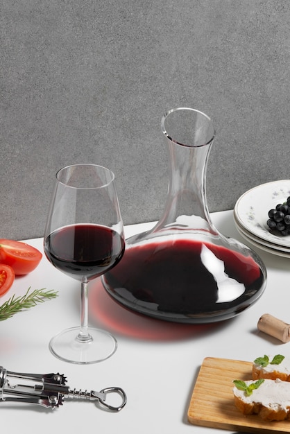 Foto gratuita jarra de vino de alto ángulo y copa en la mesa