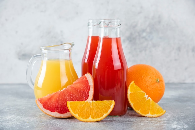 Foto gratuita jarras de vidrio de jugo de toronja con rodajas de frutas de naranja.