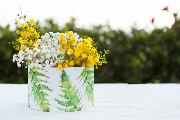 Jarrón bonito con flores amarillas y blancas