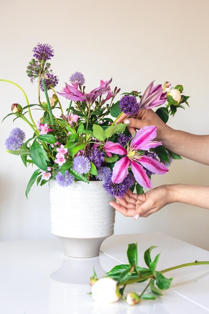 Jarrón con flores frescas de verano en manos femeninas sobre un fondo blanco.