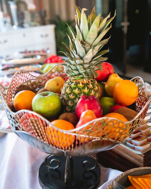 jarrón de frutas con piña, naranjas, manzanas, peras y kiwi