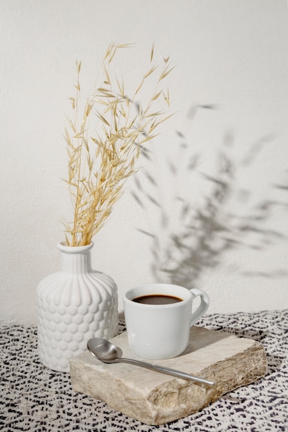 Jarrón con trigo seco y taza de café.