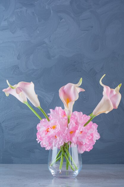 Un jarrón de vidrio con un ramo de hermosas flores frescas de color rosa.