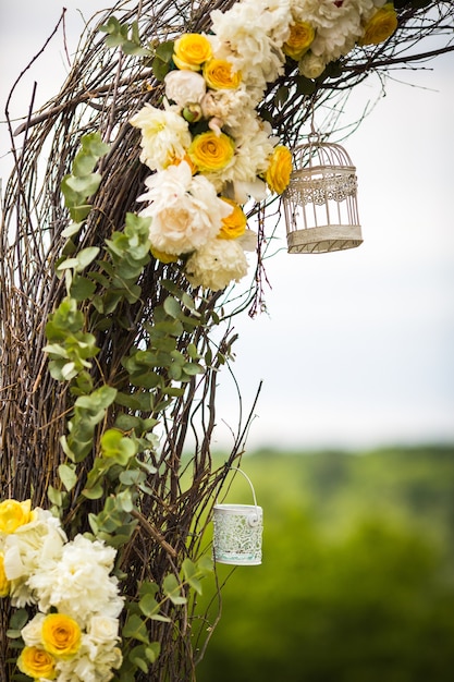 Las jaulas de pájaros blancas decorativas cuelgan en el altar de la boda de mimbre