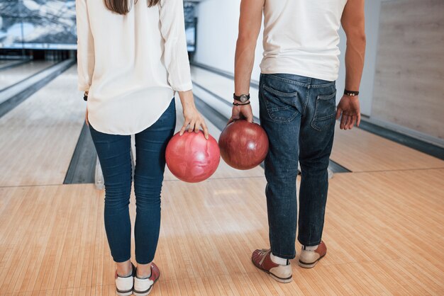 En jeans y camisas blancas. Vista recortada de personas en el club de bolos listas para divertirse