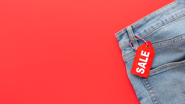 Jeans de vista superior con etiqueta de venta sobre fondo rojo