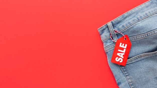Jeans de vista superior con etiqueta de venta sobre fondo rojo