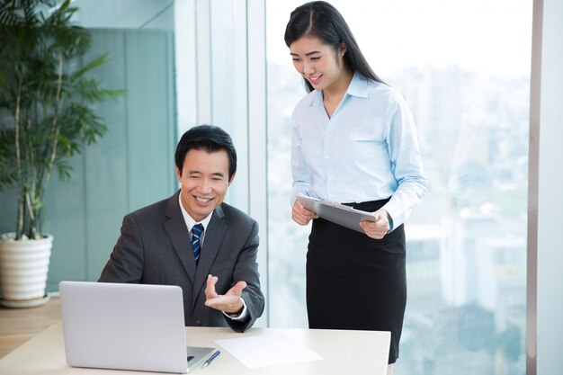 Jefe de Asia discusión de ideas con asistente femenina