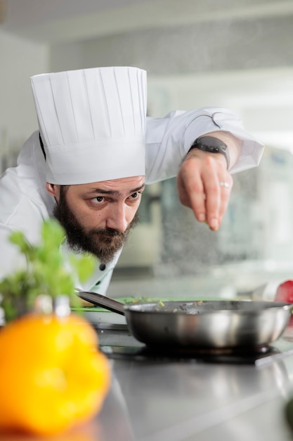 Jefe de cocina adornando un delicioso plato de cena gourmet con queso parmesano en la cocina del restaurante. Trabajador de la industria alimentaria caucásica cocinando con hierbas frescas y verduras orgánicas.