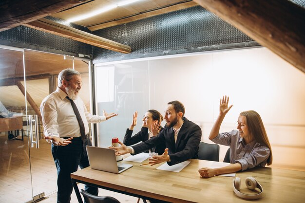 Jefe enojado con megáfono gritando a los empleados en la oficina, colegas asustados y molestos escuchando en la mesa estresados. Reunión divertida, negocios, concepto de oficina. Gritando loco.