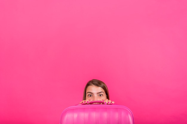 Jefe de la mujer mirando por detrás de la maleta rosa.