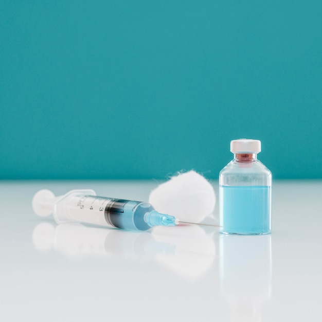 Jeringa con algodón y botella de vacuna sobre la mesa