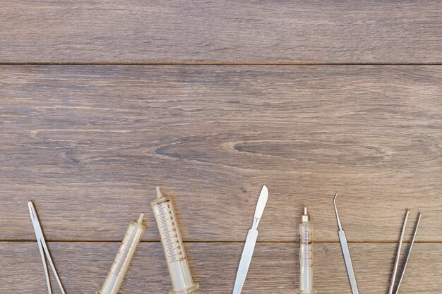 Jeringa de plástico vacía e instrumentos quirúrgicos en escritorio de madera