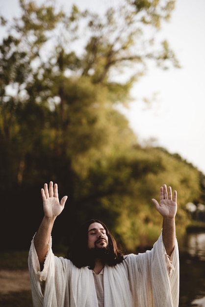 Foto gratuita jesucristo con las manos en alto hacia el cielo mientras sus ojos están cerrados