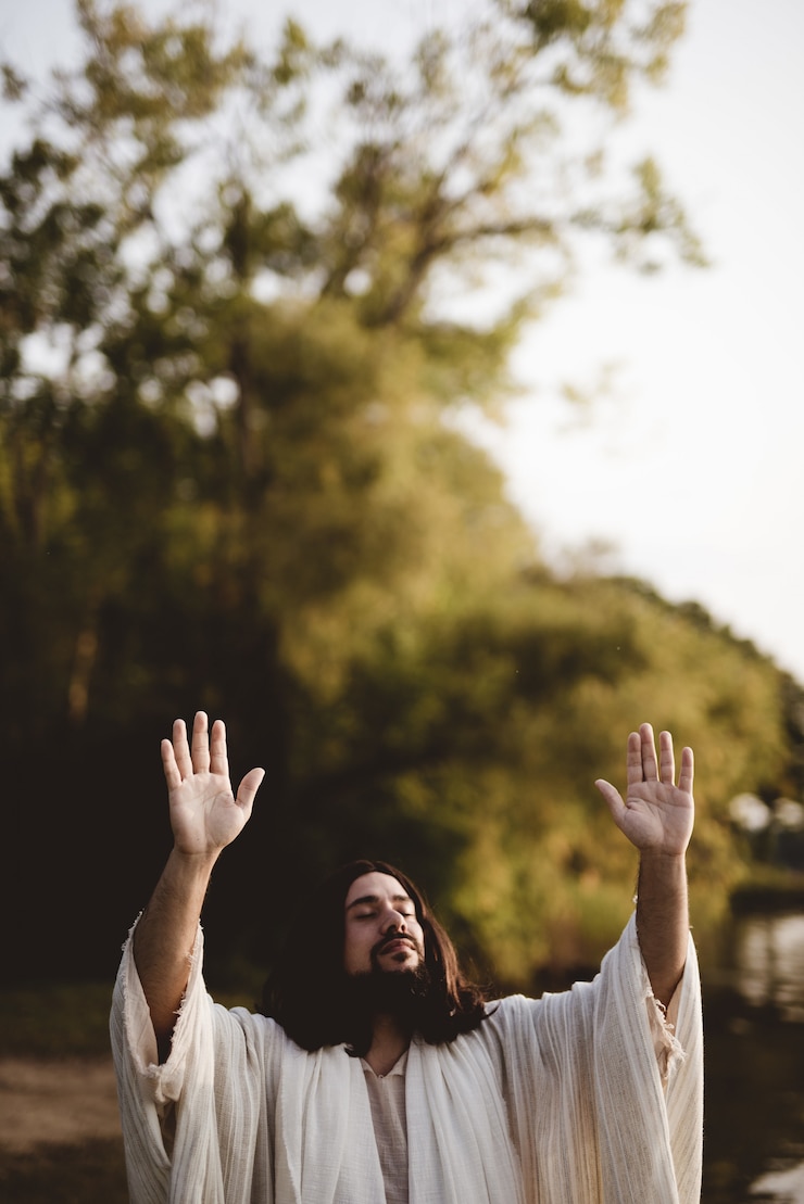 Foto gratuito jesucristo con las manos en alto hacia el cielo mientras sus ojos están cerrados