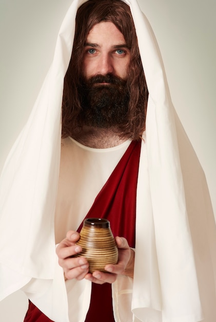 Foto gratuita jesús vistiendo túnica sosteniendo agua bendita en la jarra