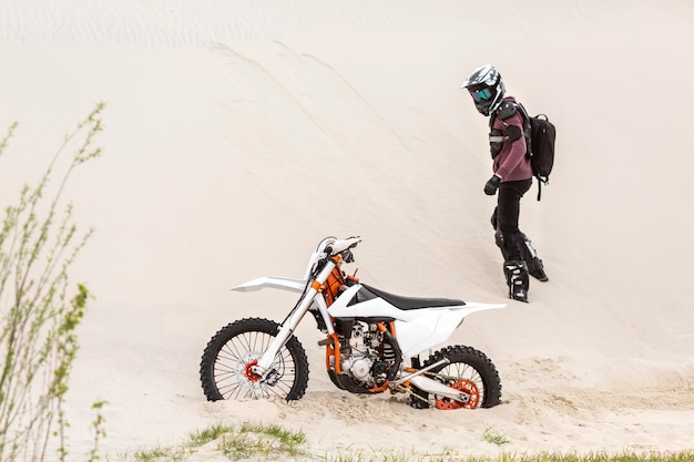 Jinete activo mirando su moto en el desierto