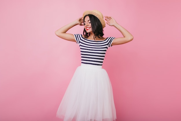 Foto gratuita jocund mujer latina con cabello negro posando con los ojos cerrados. retrato de interior de una chica bastante bronceada disfrutando de la sesión de fotos.