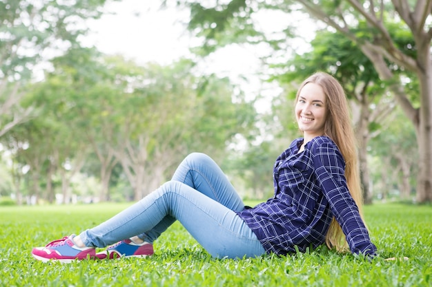 Jolly hermosa adolescente sentado en la hierba