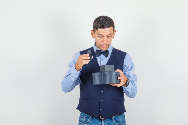 Joven abriendo la caja actual en traje, jeans y mirando sorprendido