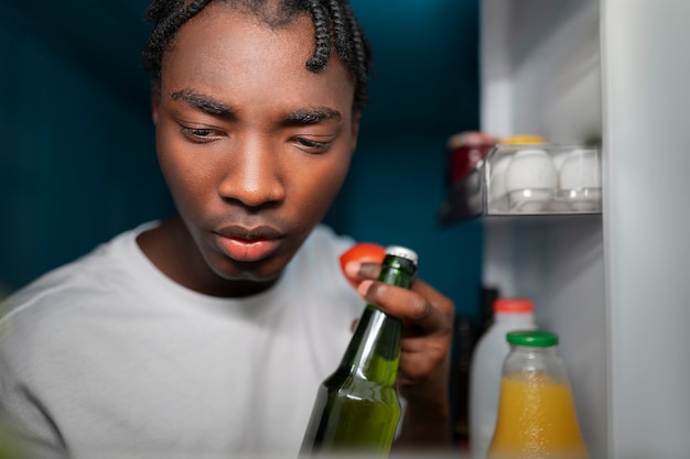 Foto gratuita joven abriendo la nevera en casa para tomar un refrigerio en medio de la noche