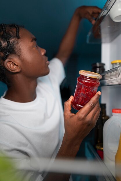 Joven abriendo la nevera en casa para tomar un refrigerio en medio de la noche