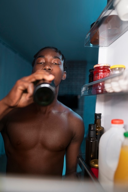 Joven abriendo la nevera en casa para tomar un refrigerio en medio de la noche