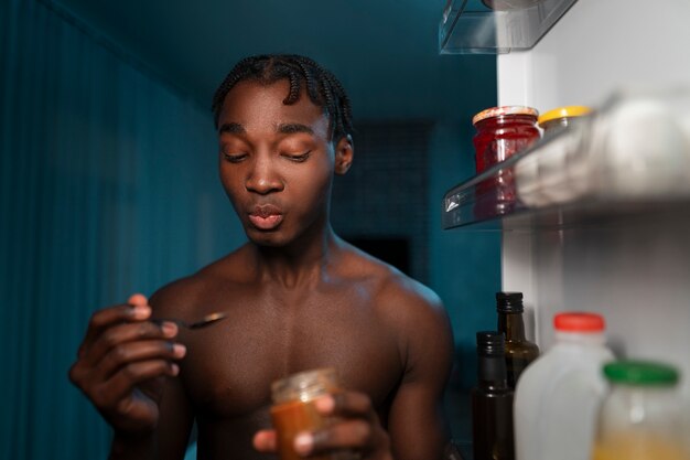 Joven abriendo la nevera en casa para tomar un refrigerio en medio de la noche