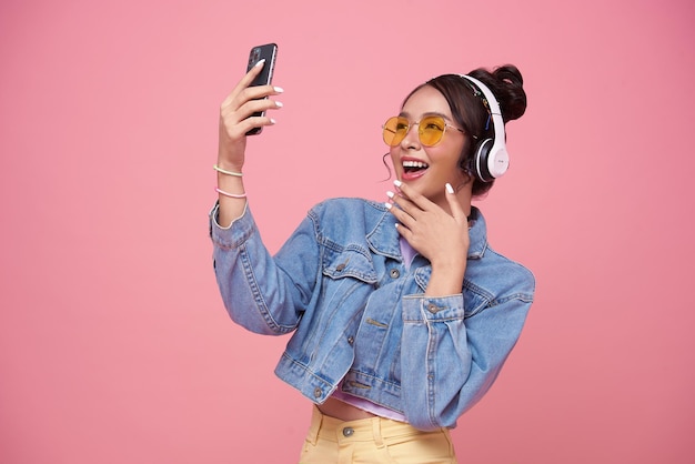 Joven adolescente asiática usando un teléfono inteligente escuchando música con auriculares