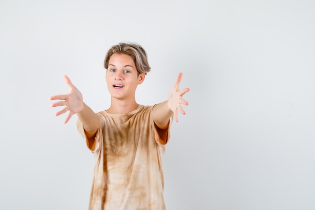 Joven adolescente en camiseta abriendo los brazos para abrazar y mirando alegre, vista frontal.