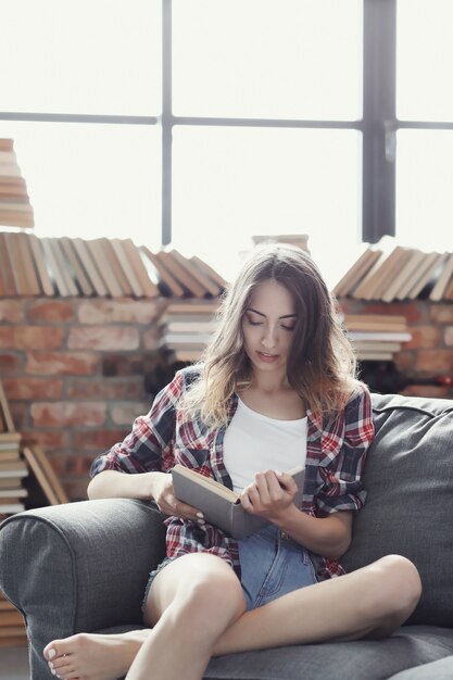 Joven adolescente leyendo un libro en casa