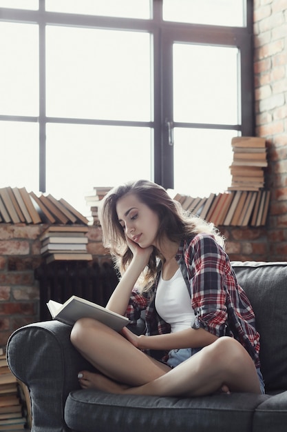 Joven adolescente leyendo un libro en casa