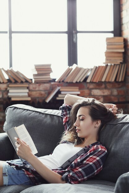 Joven adolescente leyendo un libro en casa