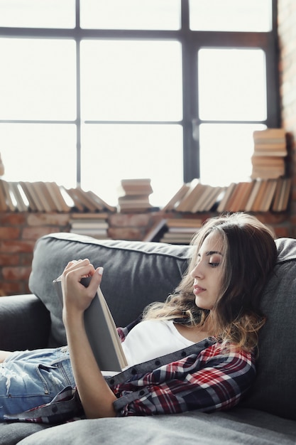 Joven adolescente leyendo un libro en casa