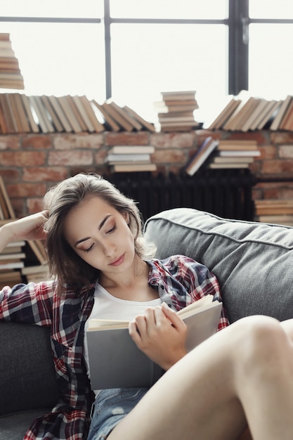 Joven adolescente leyendo un libro en casa